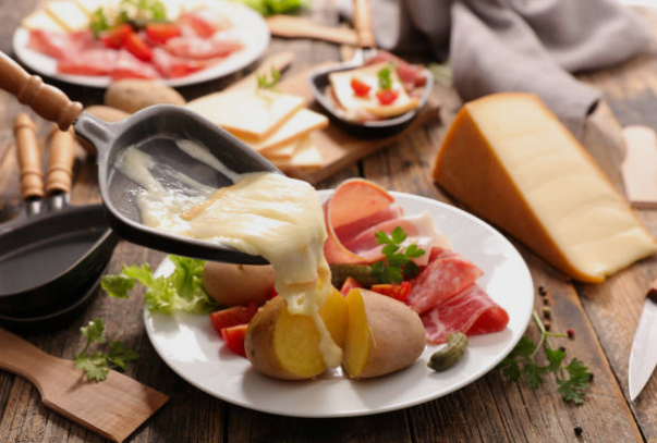 cadeaux de noël : raclette et fromage fondu qui coule sur pommes de terre et charcuterie