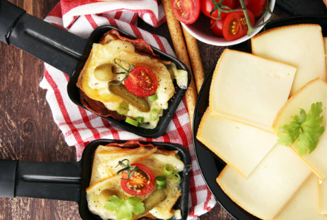 Appareil à raclette avec poelons, fromage et légumes